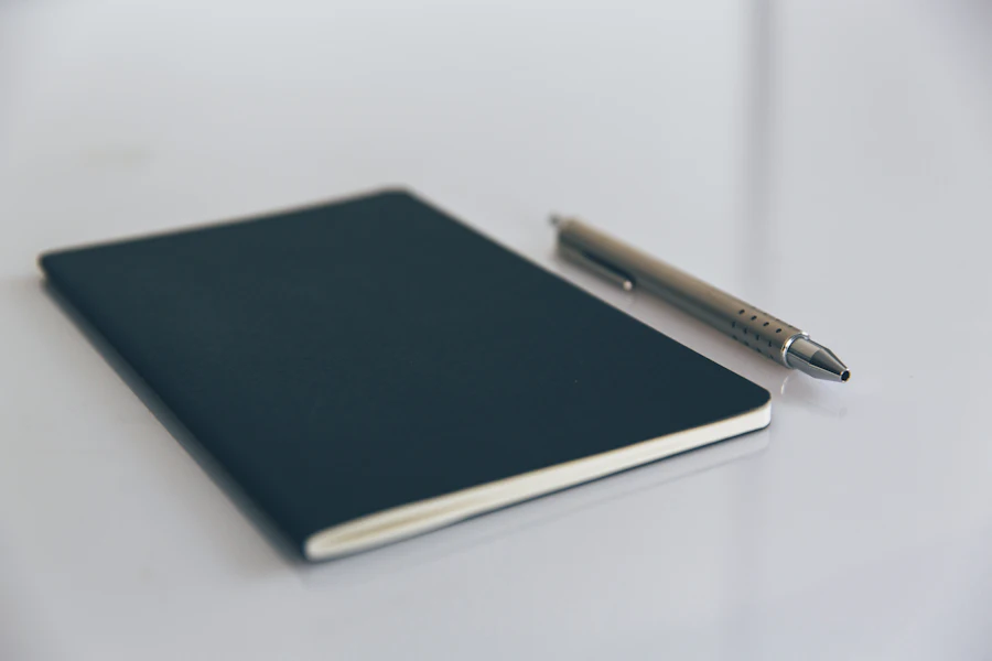 Navy notebook and pen on a white desk